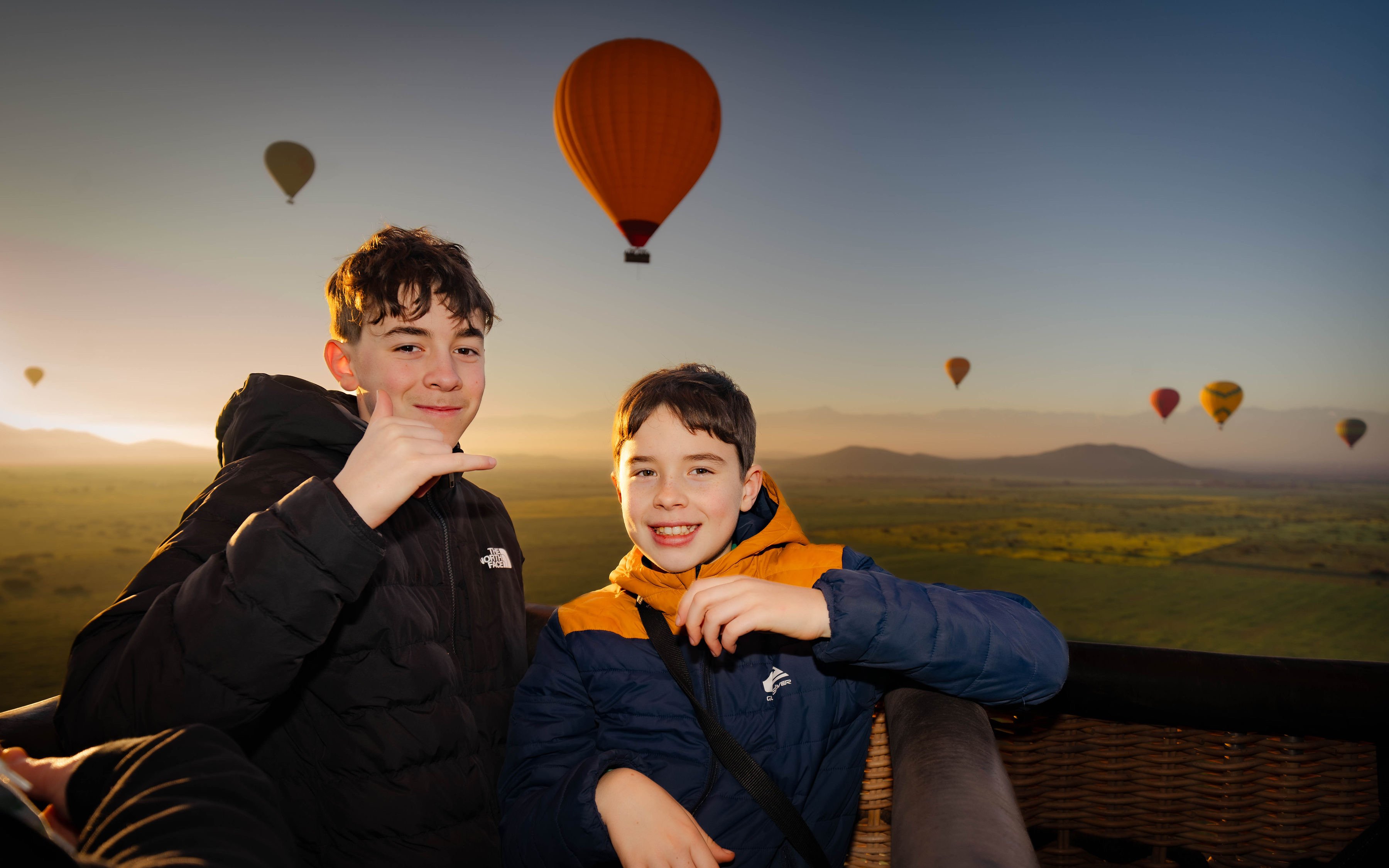 Kids enjoying a hot air balloon flight over Marrakech at sunrise.