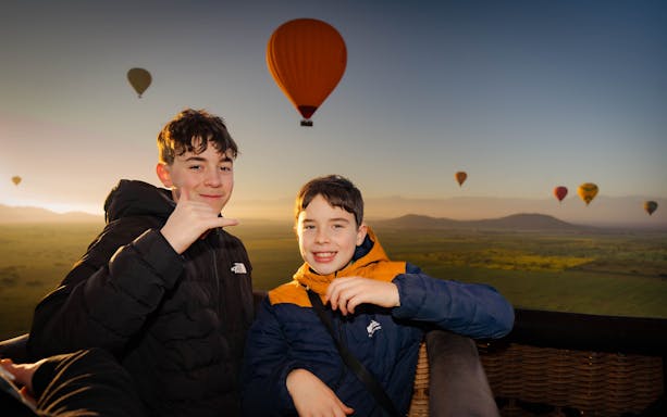 Kids enjoying a hot air balloon flight over Marrakech at sunrise.