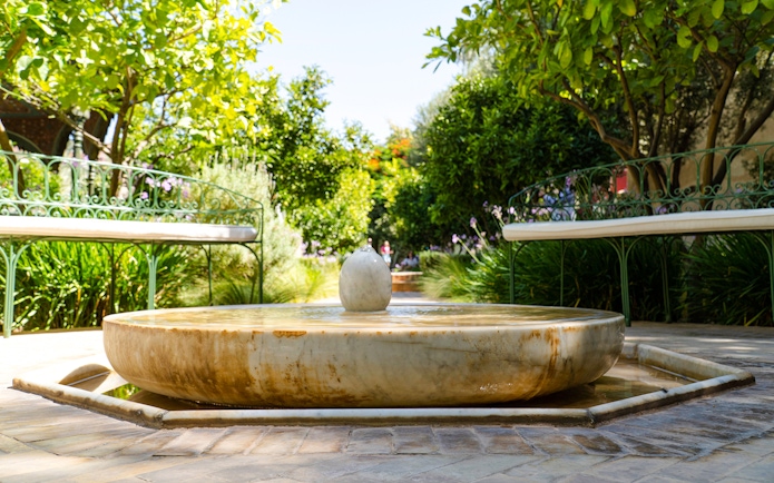 Fountain in Jardin Secret surrounded by greenery, part of the Khettara water system.