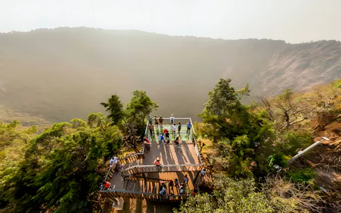Visitors on a viewing platform overlooking El Boquerón Volcano crater, surrounded by lush greenery.