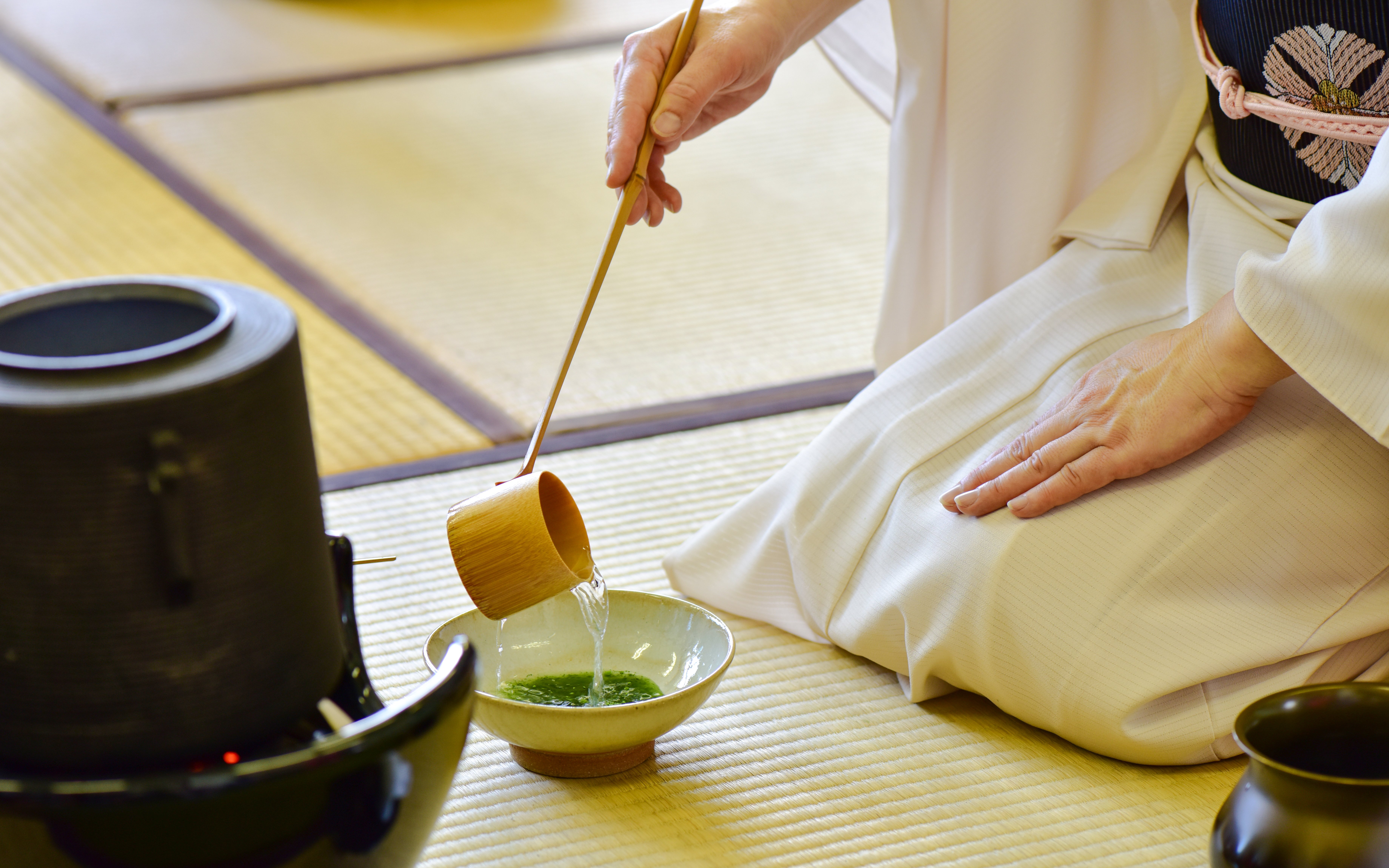 Kimono-clad person performing tea ceremony with matcha in Tokyo.