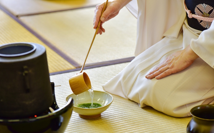 Kimono-clad person performing tea ceremony with matcha in Tokyo.
