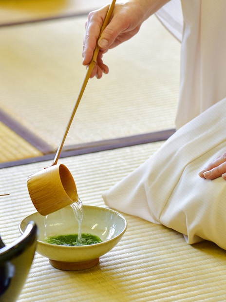 Kimono-clad person performing tea ceremony with matcha in Tokyo.
