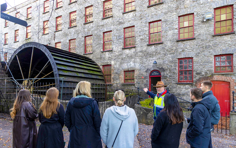 Tour group at Midleton Distillery's historic waterwheel with guide explaining its significance.