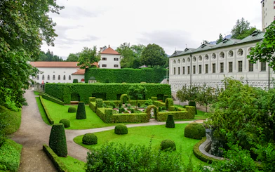 Ambras Castle Innsbruck gardens with manicured hedges and historic architecture.