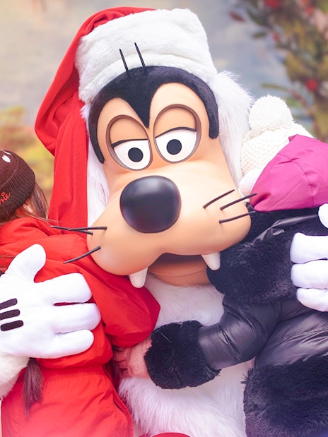 Goofy hugging children at Disneyland during Christmas 2025 celebrations.