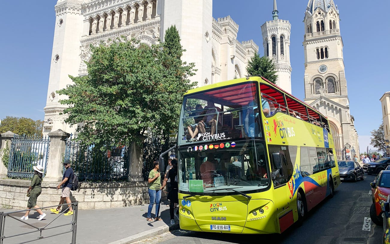 Open-top Lyon city tour bus near Basilica of Notre-Dame de Fourvière, France.