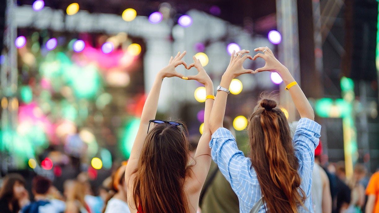 Fans making heart shapes with hands at a vibrant K-pop concert.