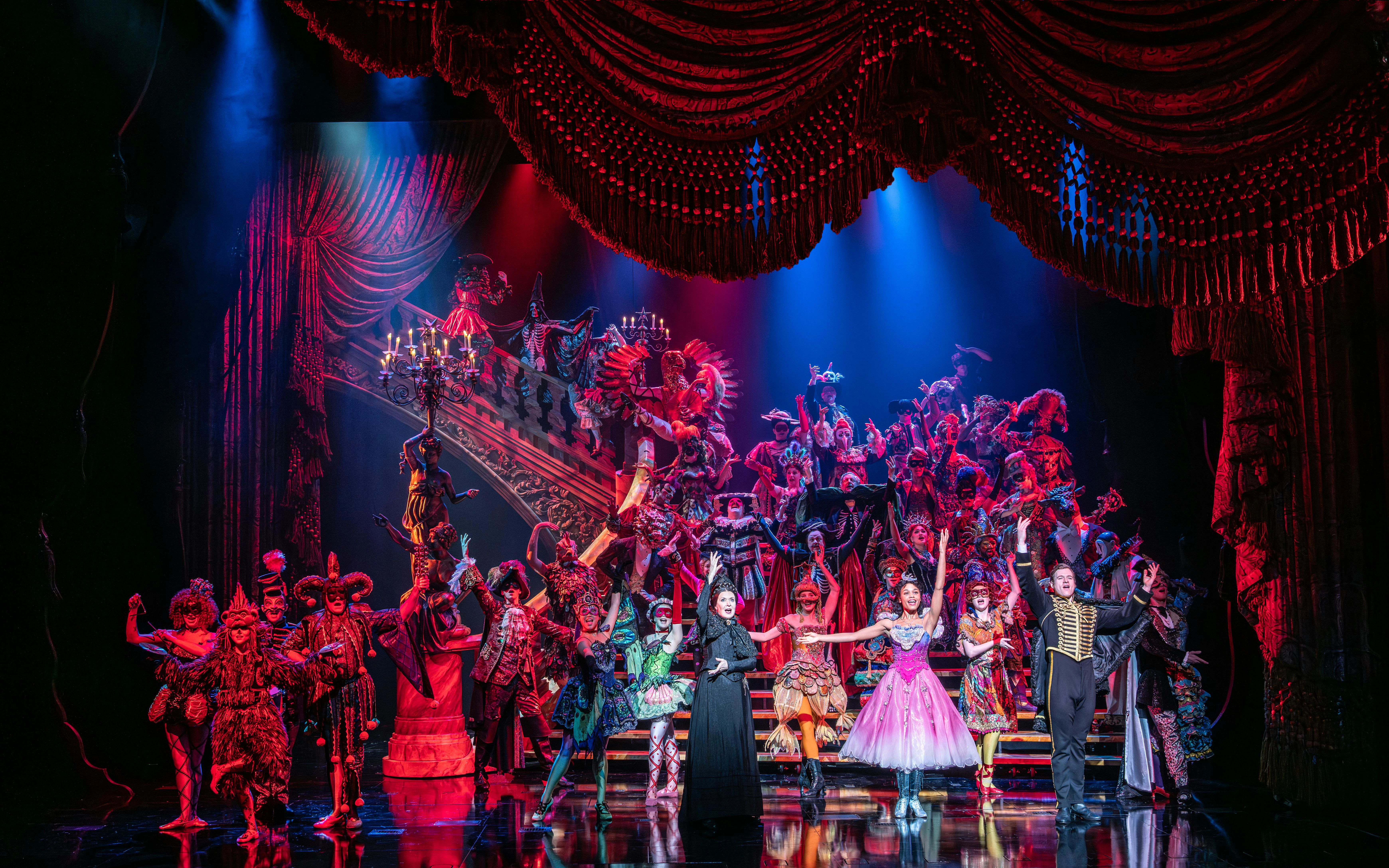 Performers in elaborate costumes on stage during a Phantom production.
