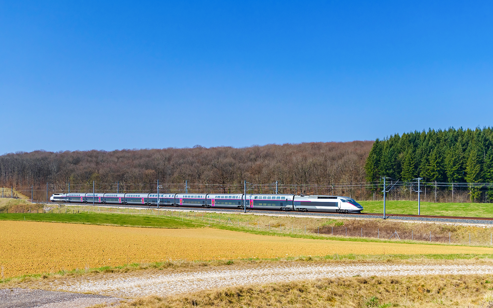 High-speed train traveling through rural Northern France landscape.