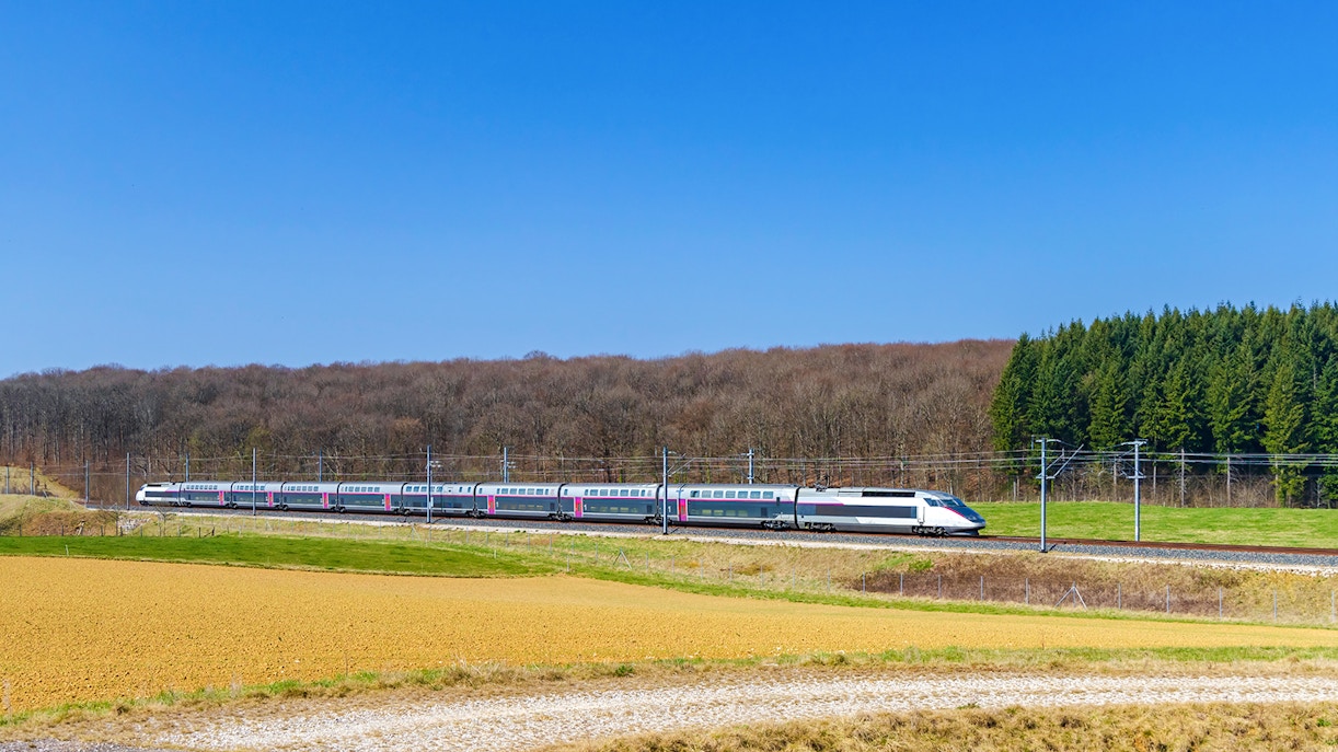 High-speed train traveling through rural Northern France landscape.