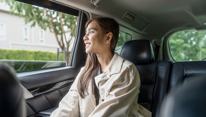 Female guest enjoying taxi ride looking out the window.