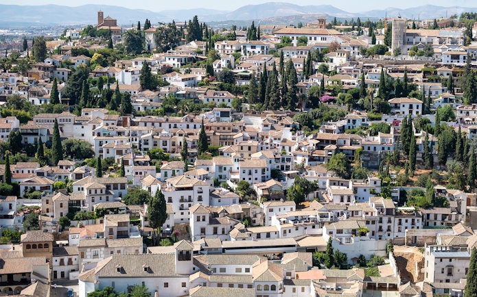 Granada's Albaicín district with traditional white houses and cypress trees near Alhambra.