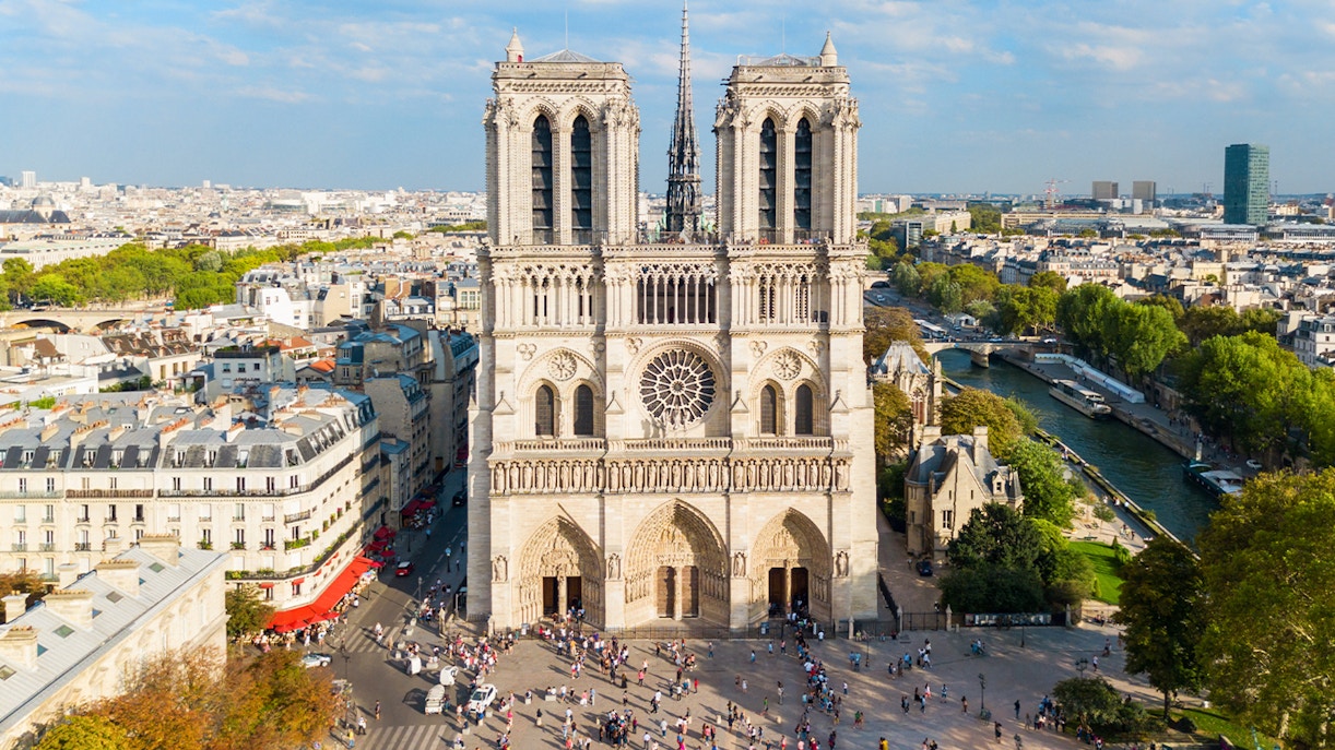 Notre Dame de Paris facade with tourists walking nearby, Paris, France.