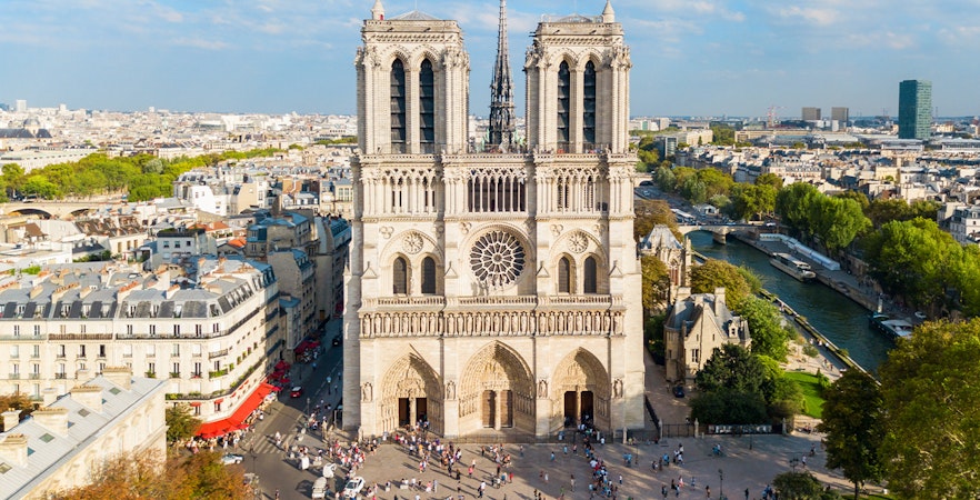 Notre Dame de Paris facade with tourists walking nearby, Paris, France.