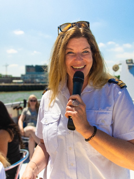 Live guide speaking on a River Cruise in Rotterdam with passengers in the background.