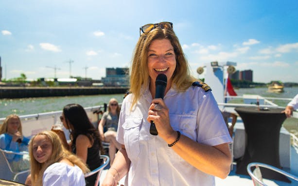 Live guide speaking on a River Cruise in Rotterdam with passengers in the background.