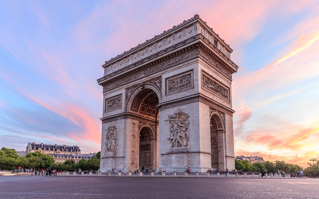 Arc de Triomphe in Paris with a colorful sunset sky.