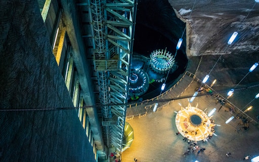 Salina Turda underground view with illuminated structures and visitors exploring the salt mine.