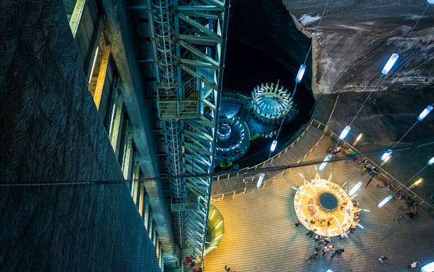 Salina Turda underground view with illuminated structures and visitors exploring the salt mine.