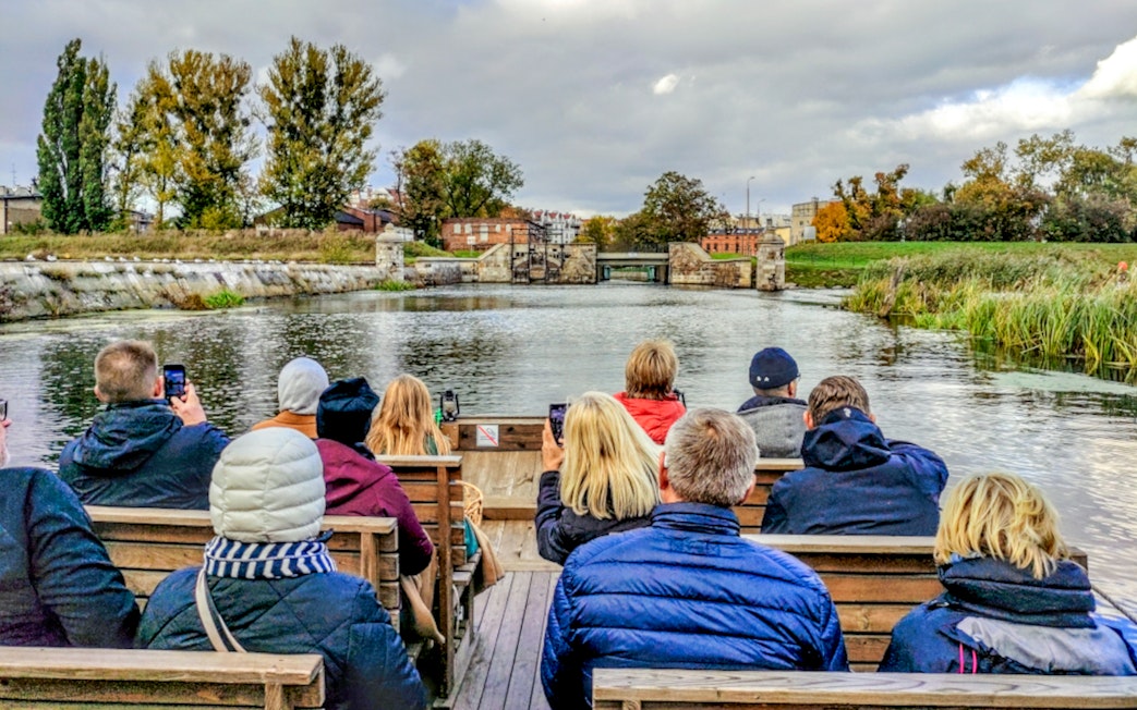 Guests enjoying a 1-hour cruise on a historical Galar boat, viewing scenic riverbanks.