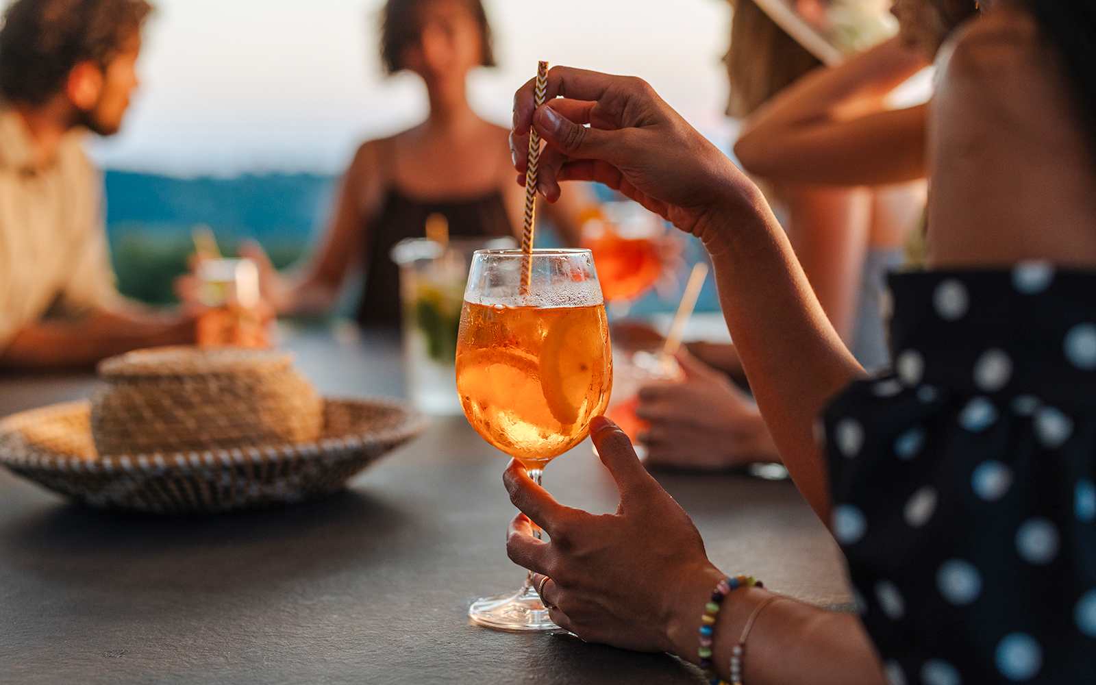 Woman enjoying aperitif cocktail at outdoor gathering.