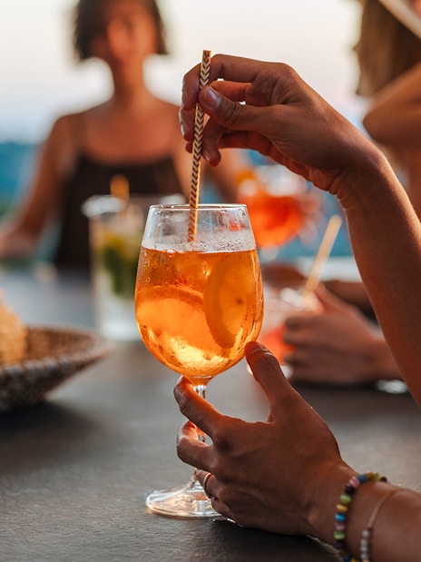 Woman enjoying aperitif cocktail at outdoor gathering.