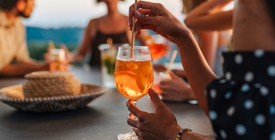 Woman enjoying aperitif cocktail at outdoor gathering.
