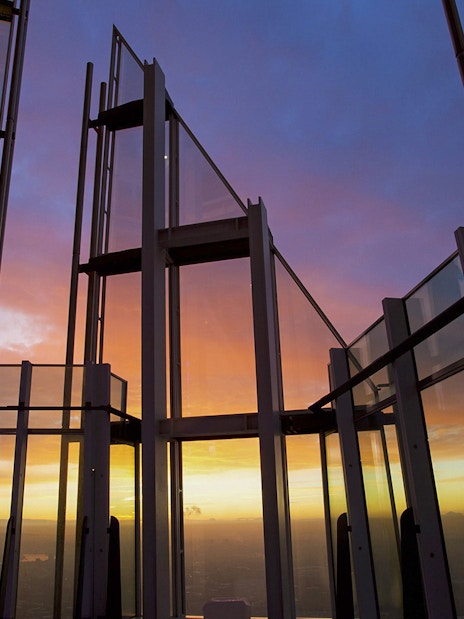 Glass observation deck at sunset with city view.