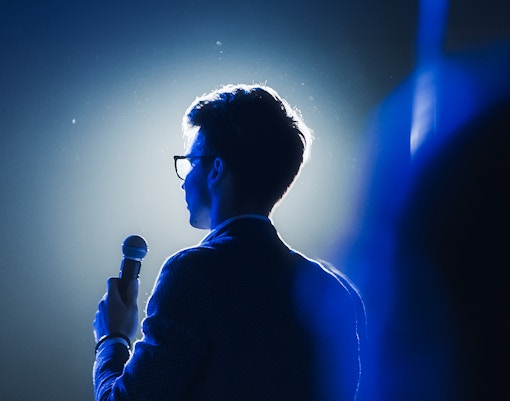 Comedian on stage holding a microphone during a comedy show.