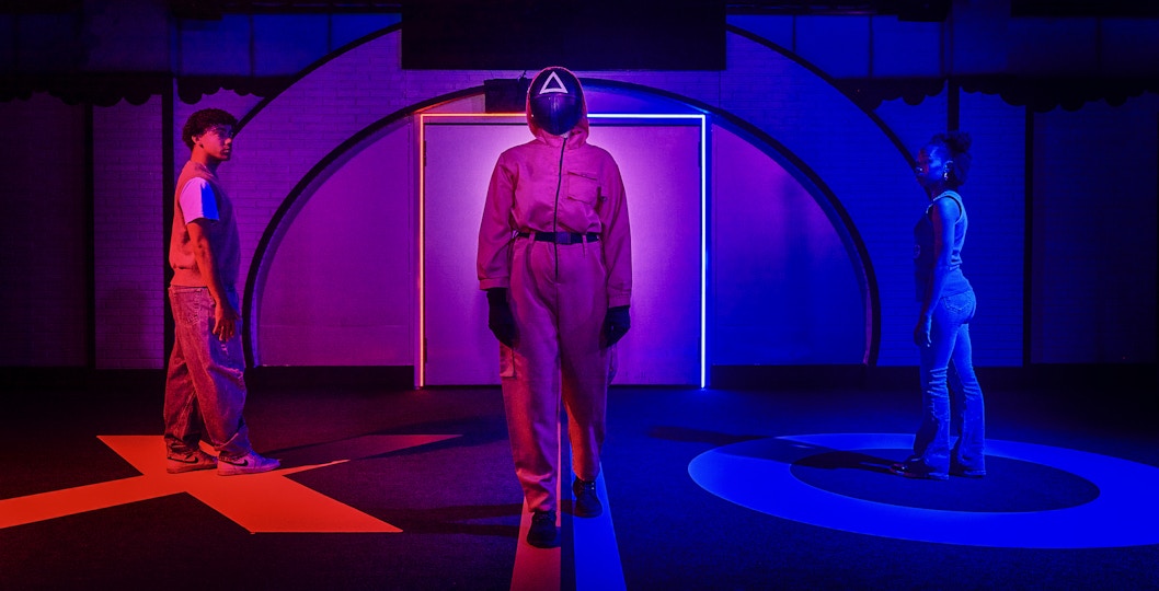 Participants in a Squid Game-themed experience in London, standing in a neon-lit room.