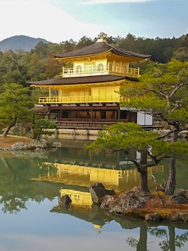 Kinkakuji Temple reflecting in a serene pond surrounded by trees in Kyoto, Japan.