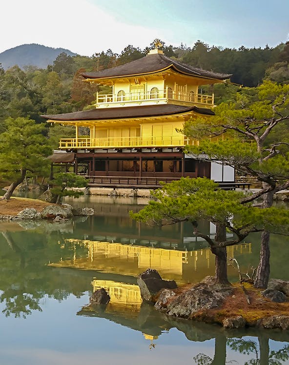 Kinkakuji Temple reflecting in a serene pond surrounded by trees in Kyoto, Japan.