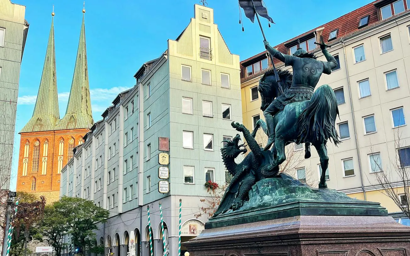 Statue of St. George slaying a dragon with Berlin's Nikolaikirche in the background.