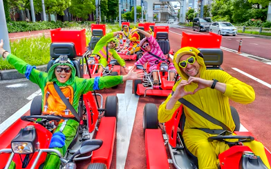 Go-kart riders in costumes driving on a street near Tokyo Bay.