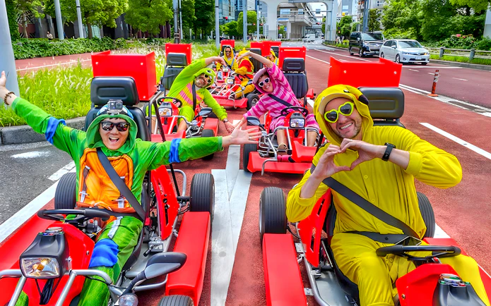 Go-kart riders in costumes driving on a street near Tokyo Bay.