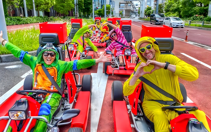 Go-kart riders in costumes driving on a street near Tokyo Bay.