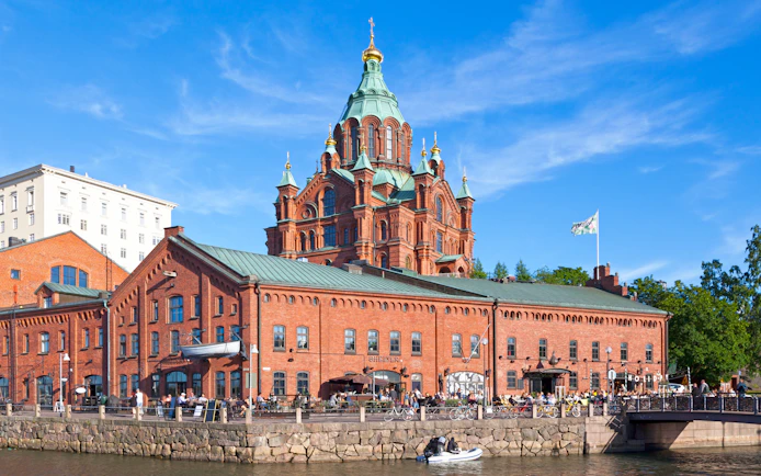 Uspenski Cathedral in Helsinki with red brick facade and green domes.
