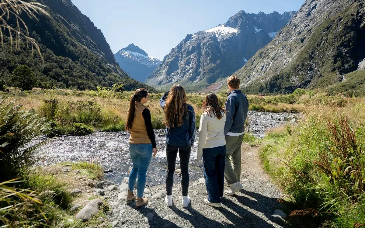 Small group exploring Milford Sound landscape with mountains and stream, Te Anau tour.