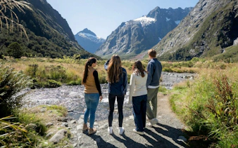 Small group exploring Milford Sound landscape with mountains and stream, Te Anau tour.