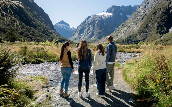 Small group exploring Milford Sound landscape with mountains and stream, Te Anau tour.