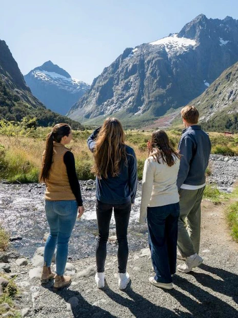 Small group exploring Milford Sound landscape with mountains and stream, Te Anau tour.
