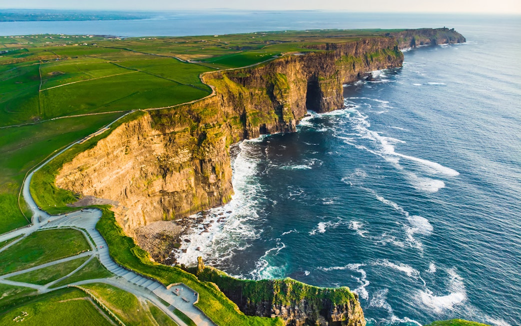 Aerial view of the Cliffs of Moher, Ireland, with waves crashing against the rocky coastline.