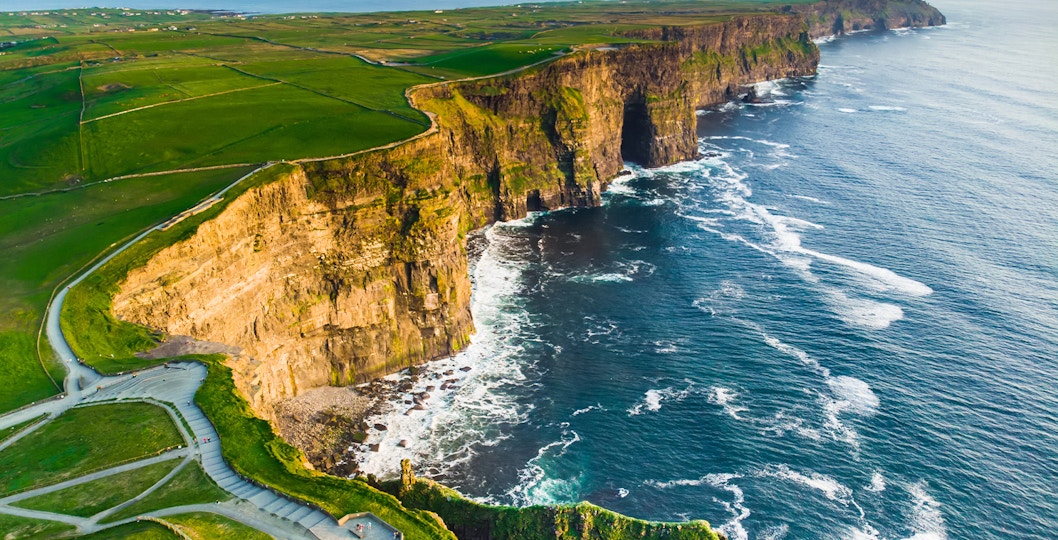 Aerial view of the Cliffs of Moher, Ireland, with waves crashing against the rocky coastline.