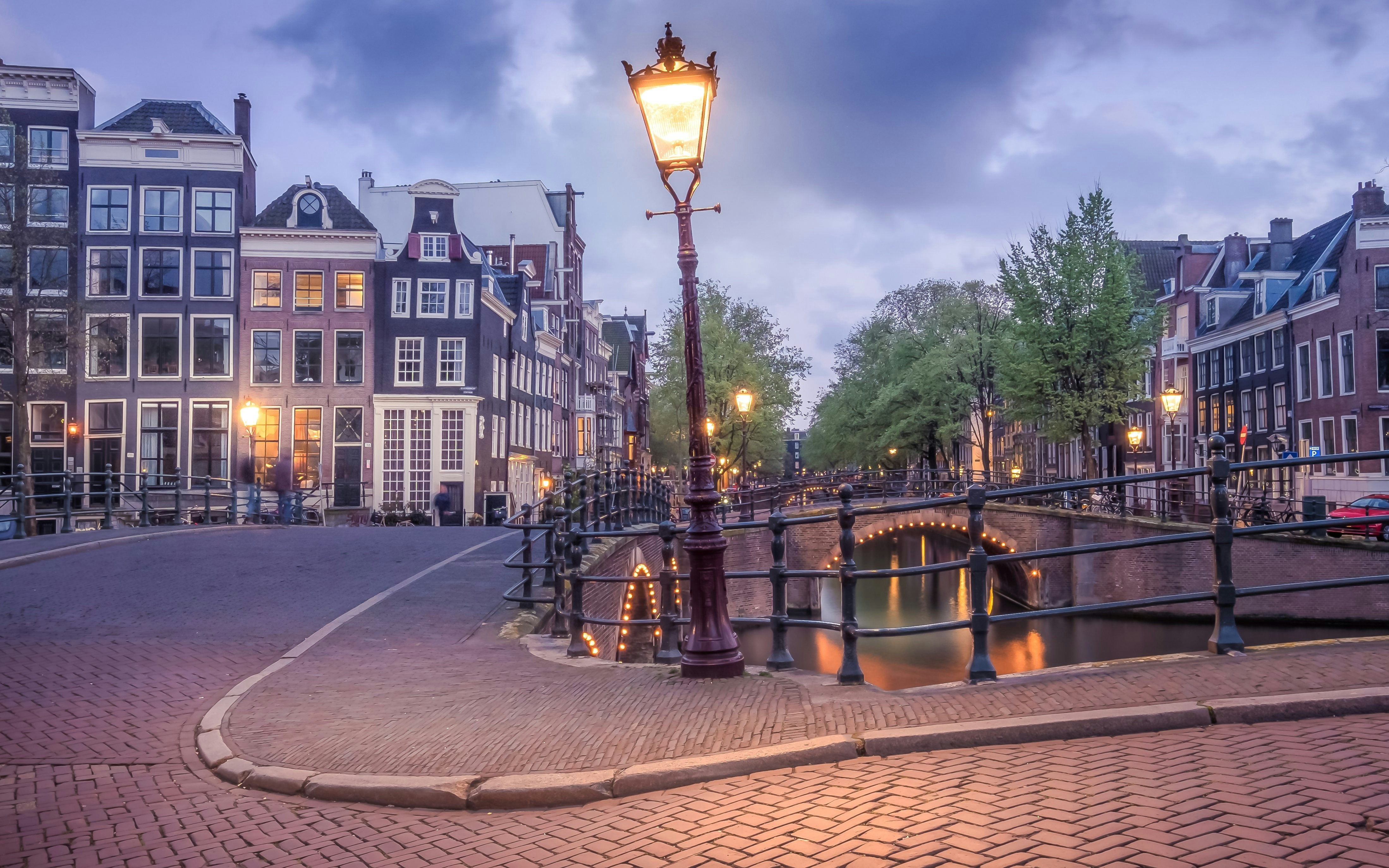 Keizersgracht canal with illuminated bridge and historic buildings in Amsterdam.
