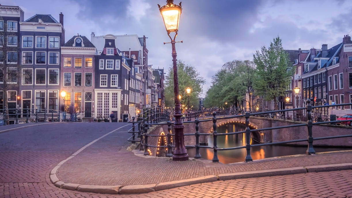 Keizersgracht canal with illuminated bridge and historic buildings in Amsterdam.
