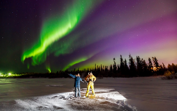 Tourist and guide viewing Northern Lights in Tromso, Norway.