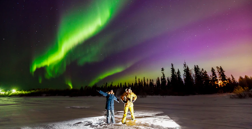 Tourist and guide viewing Northern Lights in Tromso, Norway.