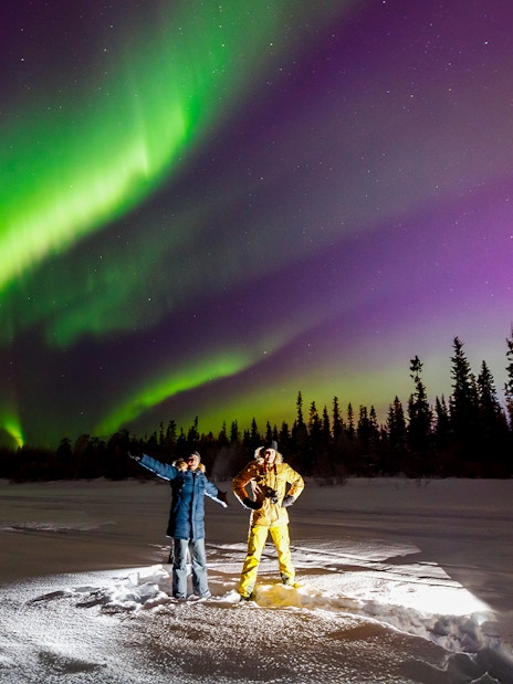 Tourist and guide viewing Northern Lights in Tromso, Norway.