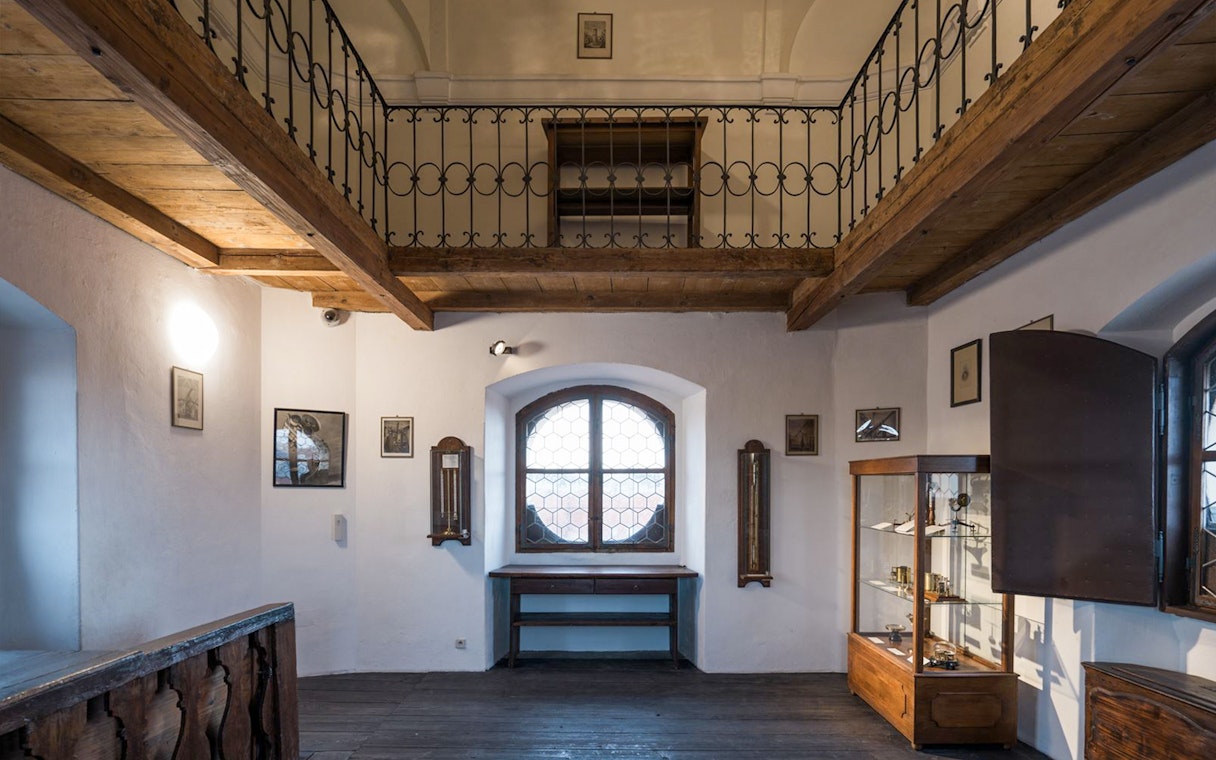 Interior view of the Astronomical Tower of Clementinum, featuring wooden beams and historical displays.